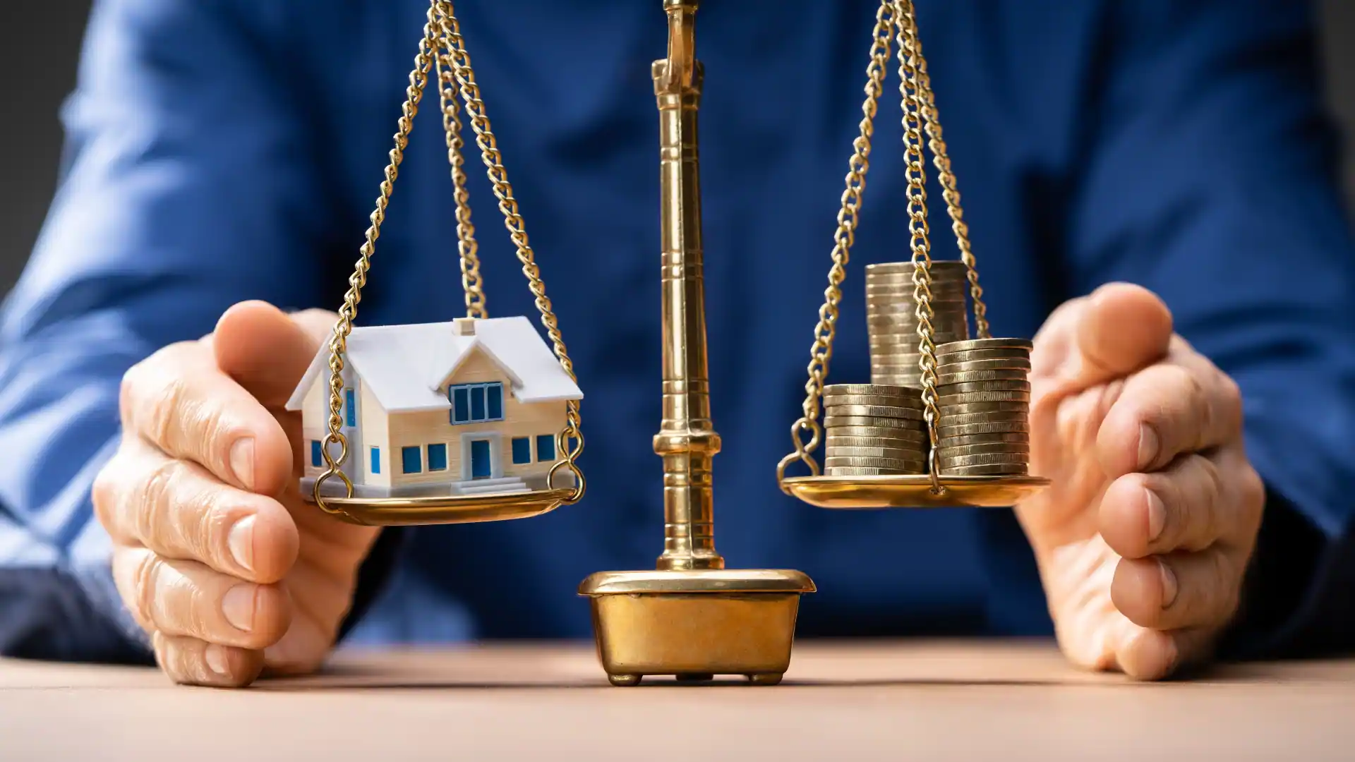 Mãos protegendo a miniatura de uma casa ao lado de uma balança da justiça, representando a defesa de direitos em questões de direito imobiliário